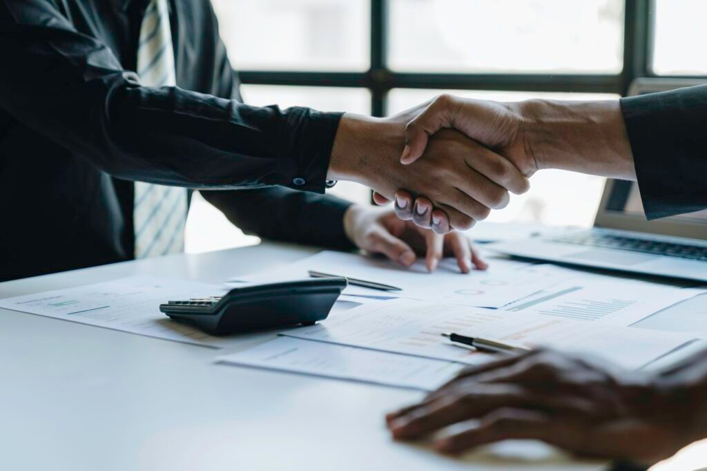 Two young Asian businessmen join hands and agree to invest in a business venture.